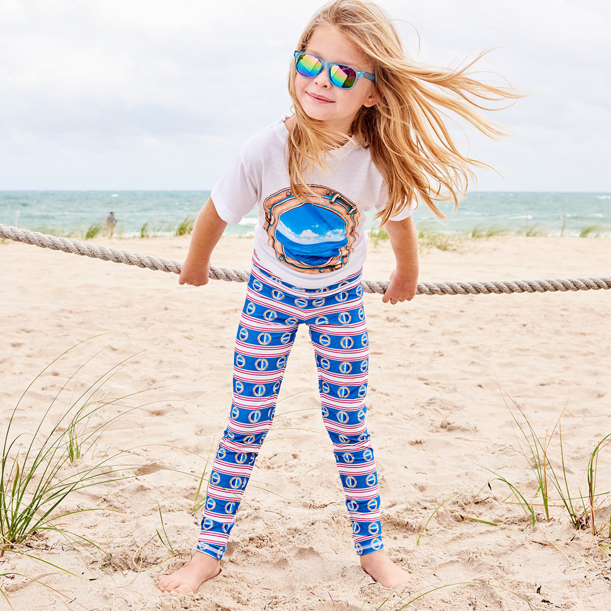 https://www.sunpoplife.com/cdn/shop/products/mariner-hybrid-youth-legging-upf50-girls-size-6-12-red-white-blue-stripes-denim-modern-mariner-girl-on-the-beach-wearing-sunglasses-playing-with-a-rope-sunpoplife.jpg?v=1523721494&width=1200